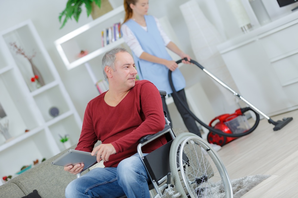 Alltagshilfe mit Staubsauger reinigt Wohnung